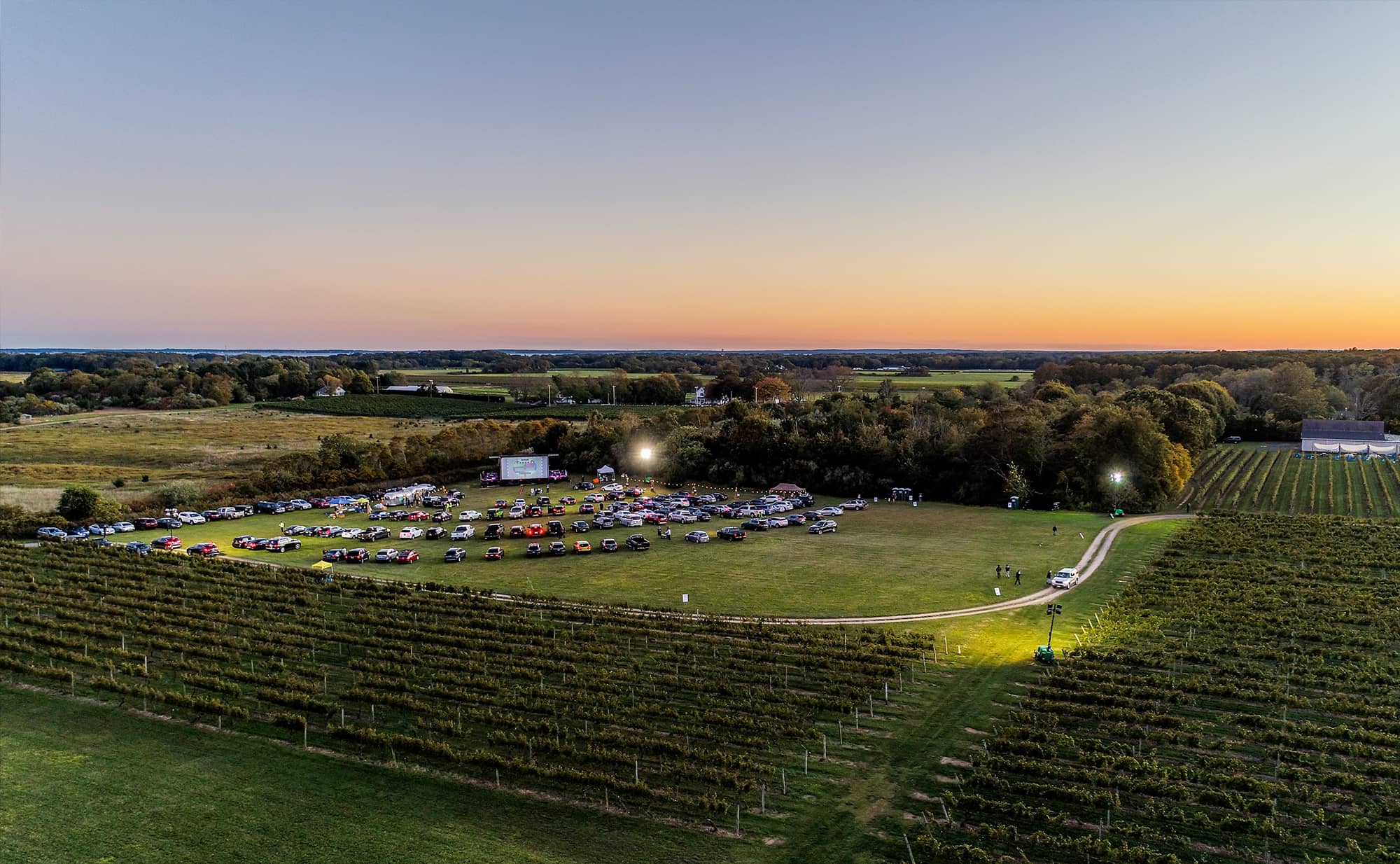Landscape of North Fork TV Festival in beautiful field with movie screen and sun setting in the background